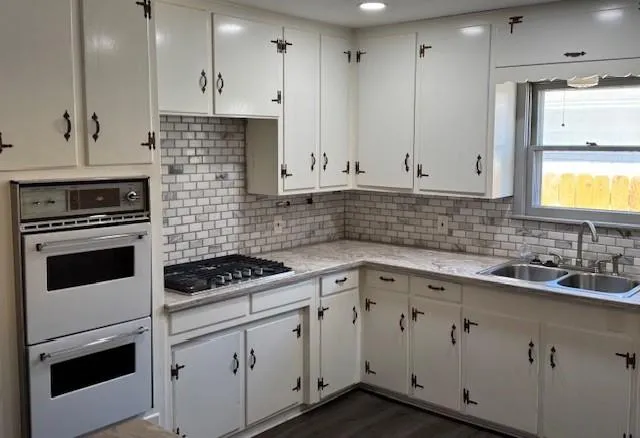 a kitchen with granite countertop white cabinets stainless steel appliances and sink