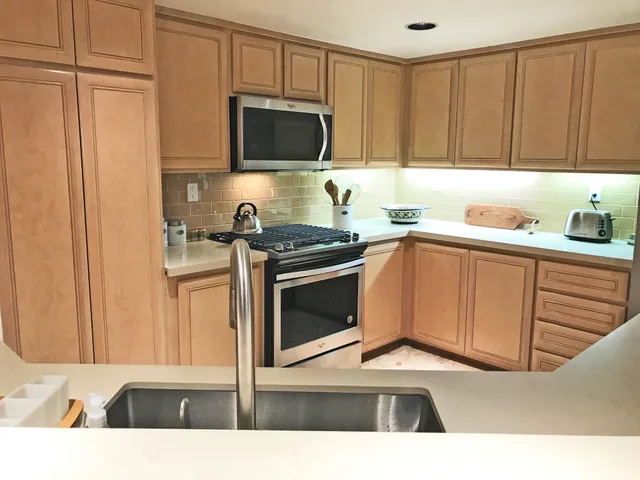 a kitchen with stainless steel appliances a stove a sink a microwave and cabinets
