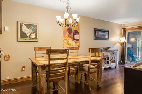 a dining room with wooden floor a chandelier a wooden table and chairs
