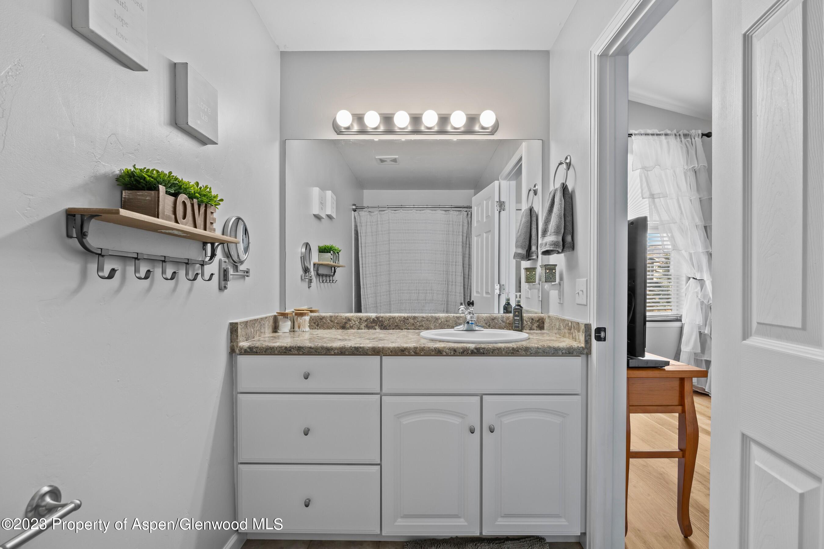 1273 East 18th Way Rifle, CO 81650 - Photo 16 of 26 a bathroom with a granite countertop sink and a mirror