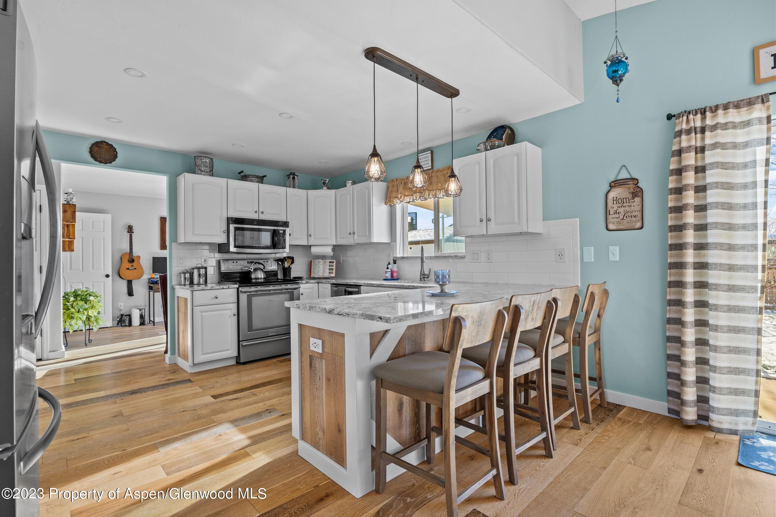 1273 East 18th Way Rifle, CO 81650 - Photo 8 of 26 a kitchen with kitchen island a stove a table and chairs in it