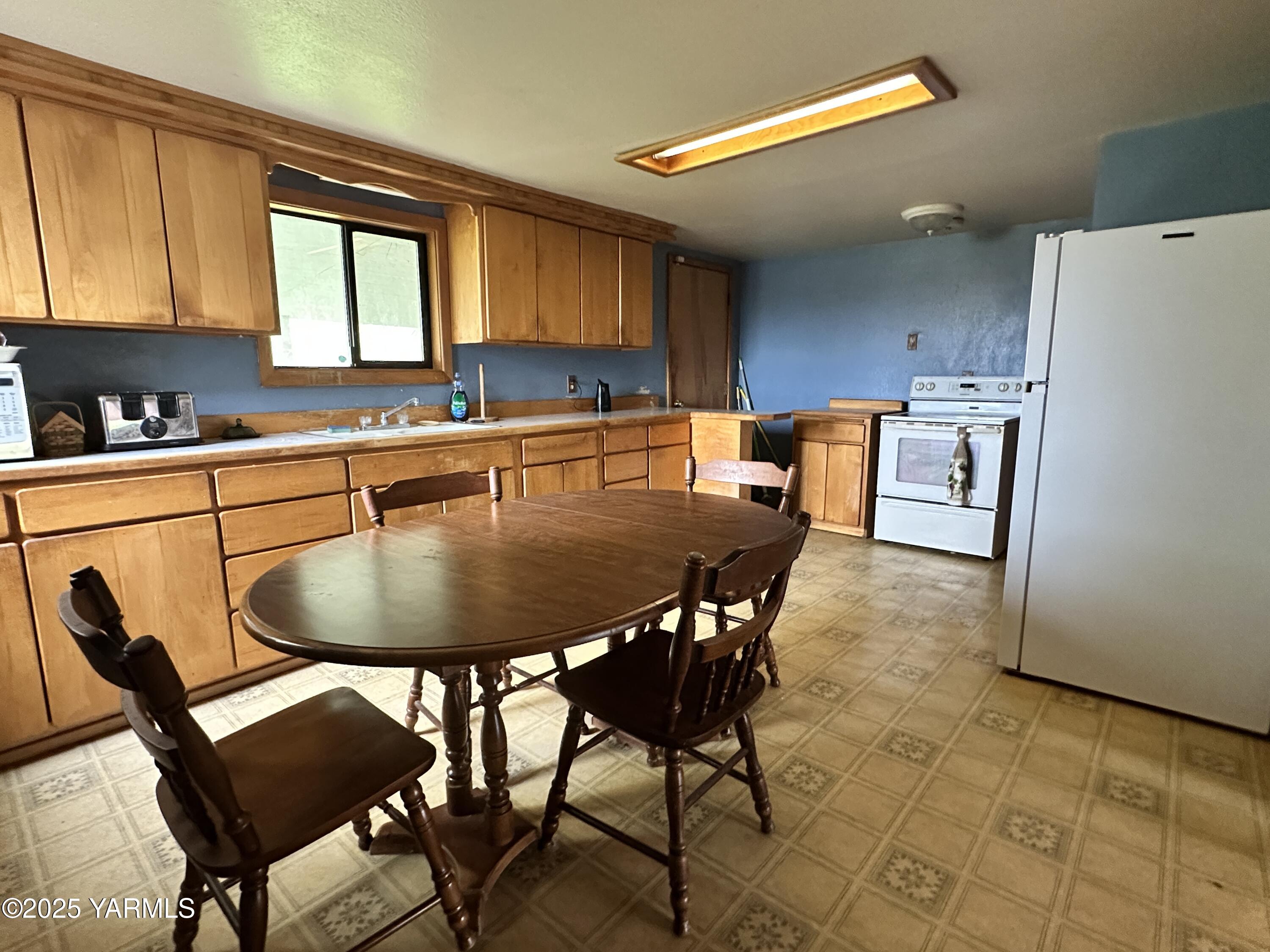 1122 McClain Drive Sunnyside, WA 98944 - Photo 3 of 8 a kitchen with a table chairs a refrigerator and a stove top oven