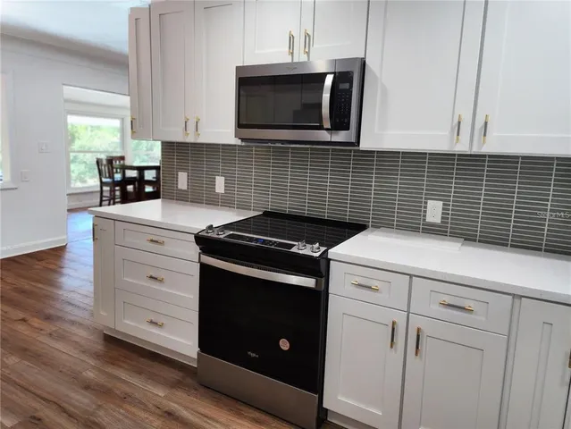 a kitchen with granite countertop cabinets stainless steel appliances and wooden floor
