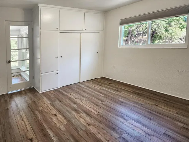 an empty room with wooden floor cabinet and windows