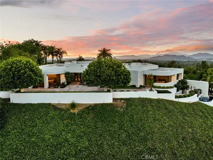 a front view of a house with a garden and a car park
