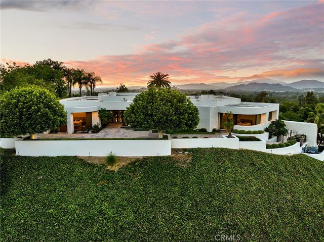 a front view of a house with a garden and a car park
