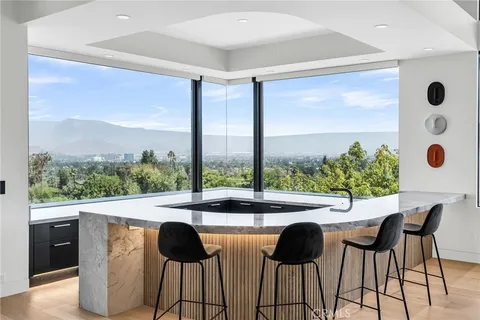 a large kitchen with kitchen island a large counter top stainless steel appliances and cabinets