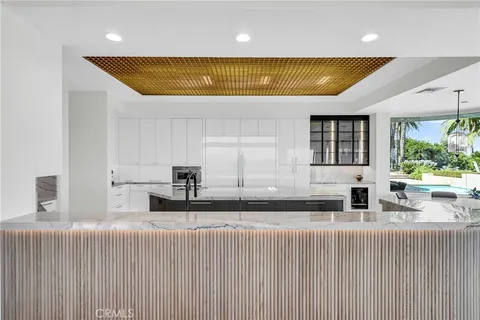 a large white kitchen with a large window and stainless steel appliances