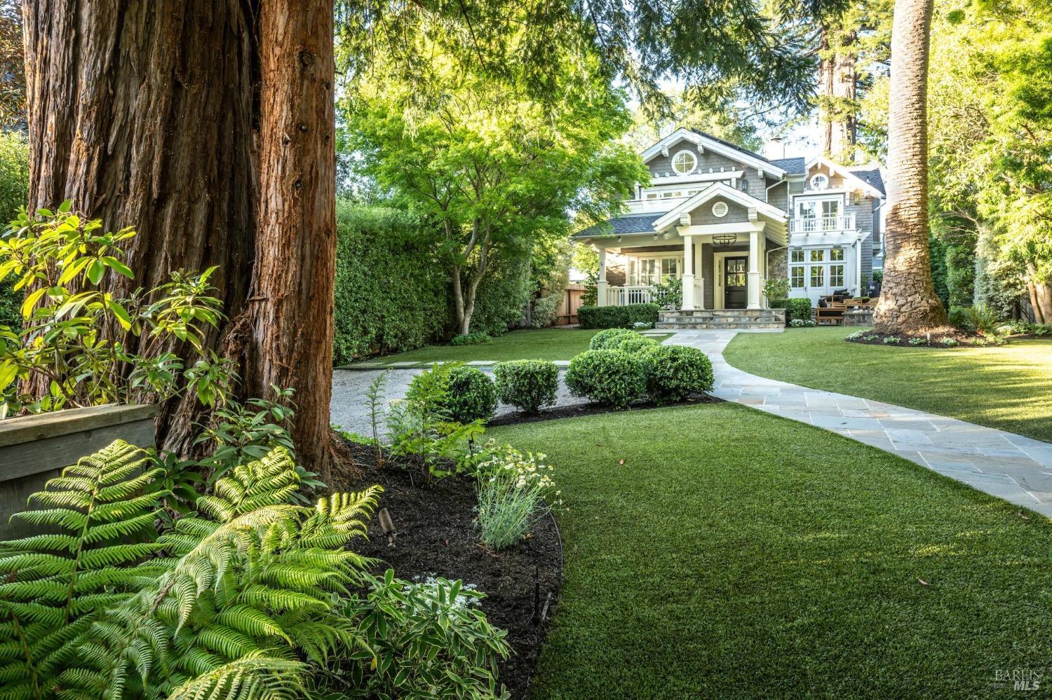 a view of a white house next to a yard with big trees