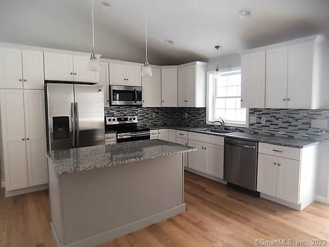 Kitchen with breakfast bar, granite countertops, stainless steel appliances and custom backsplash.