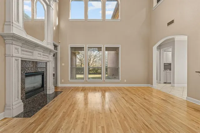 a view of an empty room with wooden floor fireplace and a window