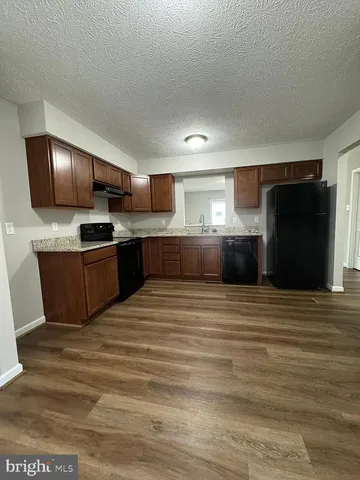 a large kitchen with kitchen island granite countertop wooden cabinets and a refrigerator