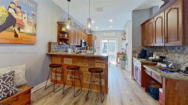 a kitchen with stainless steel appliances granite countertop a stove top oven a sink dishwasher and a dining table with wooden floor