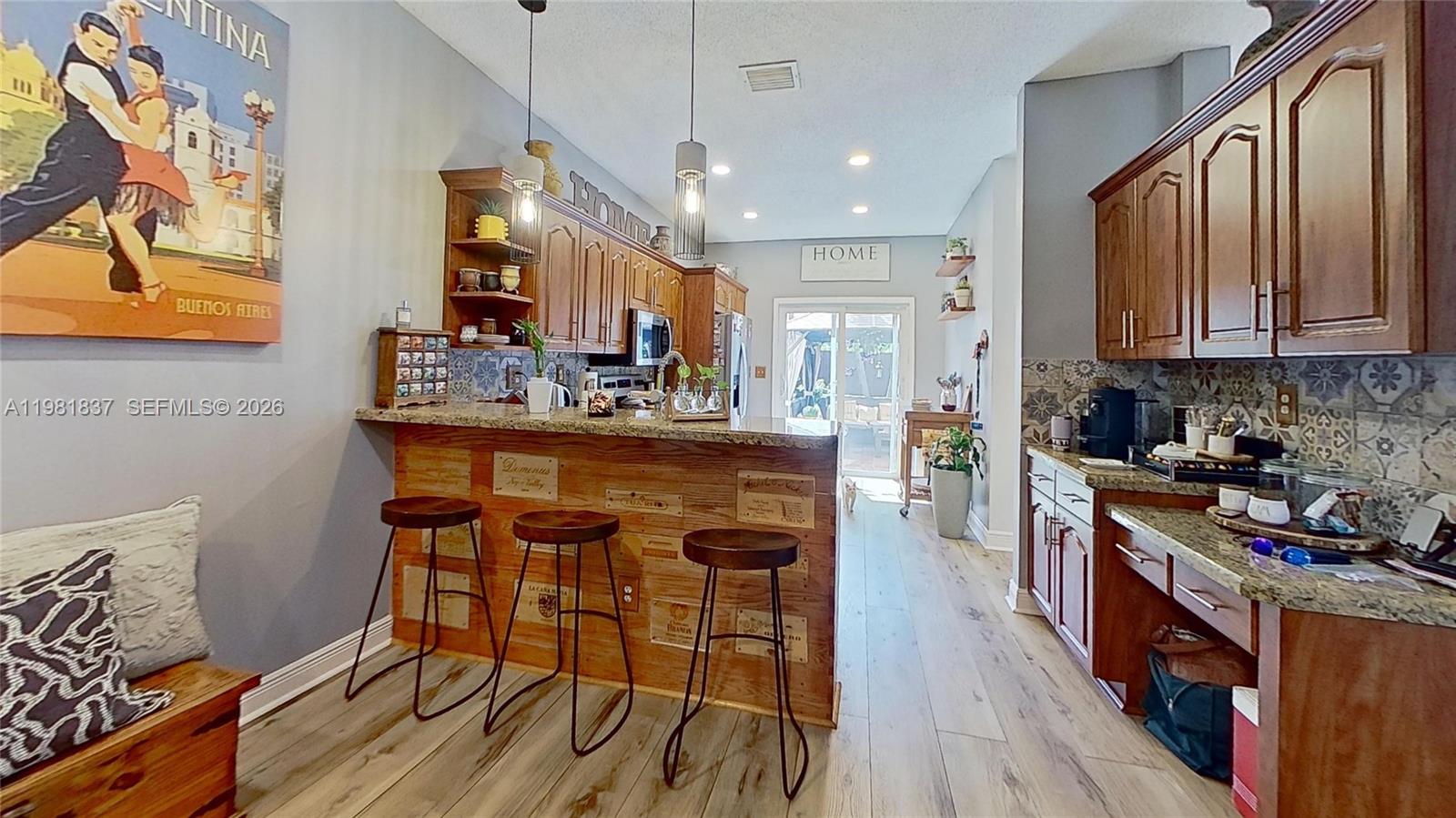 3760 Westminster Street Hollywood, FL 33021 - Photo 11 of 42 a kitchen with stainless steel appliances granite countertop a stove top oven a sink dishwasher and a dining table with wooden floor