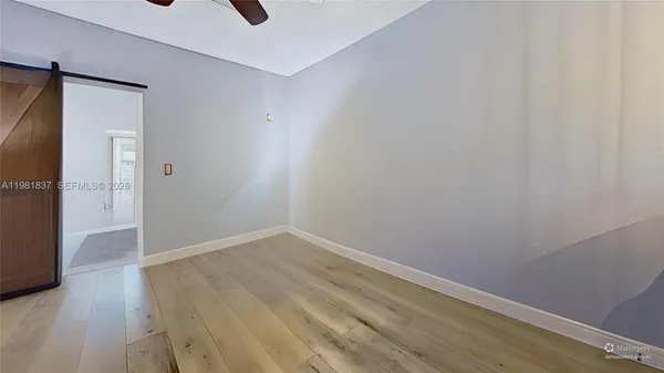 a view of an empty room with wooden floor and a window