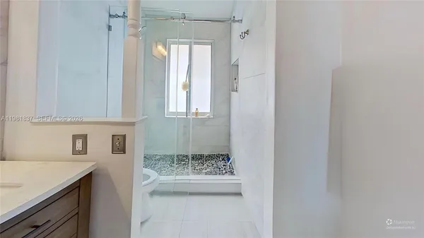 a bathroom with a granite countertop sink a toilet and shower