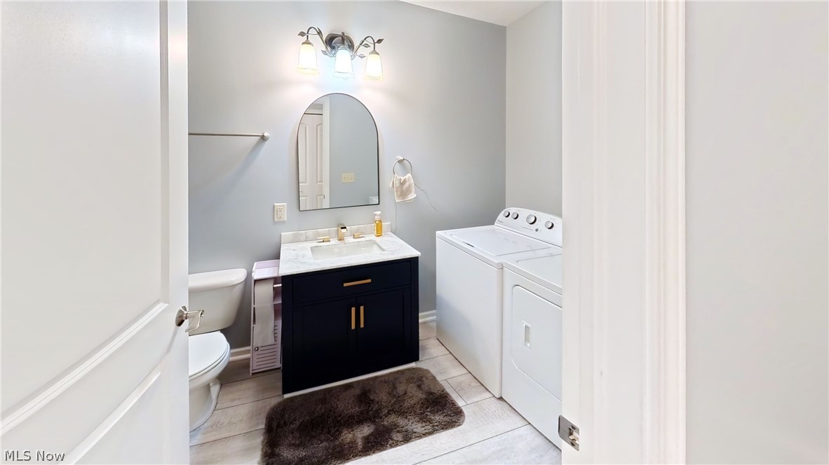 202 Home Street Rittman, OH 44270 - Photo 5 of 23 Laundry area featuring a stacked washer and dryer, a vanity with a white countertop, a basin sink, and a wall-mounted light fixture