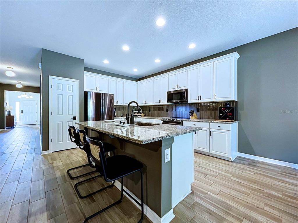 18078 Romanesque Court Spring Hill, FL 34610 - Photo 10 of 81 a kitchen with kitchen island granite countertop wooden floors stainless steel appliances a center island and chairs