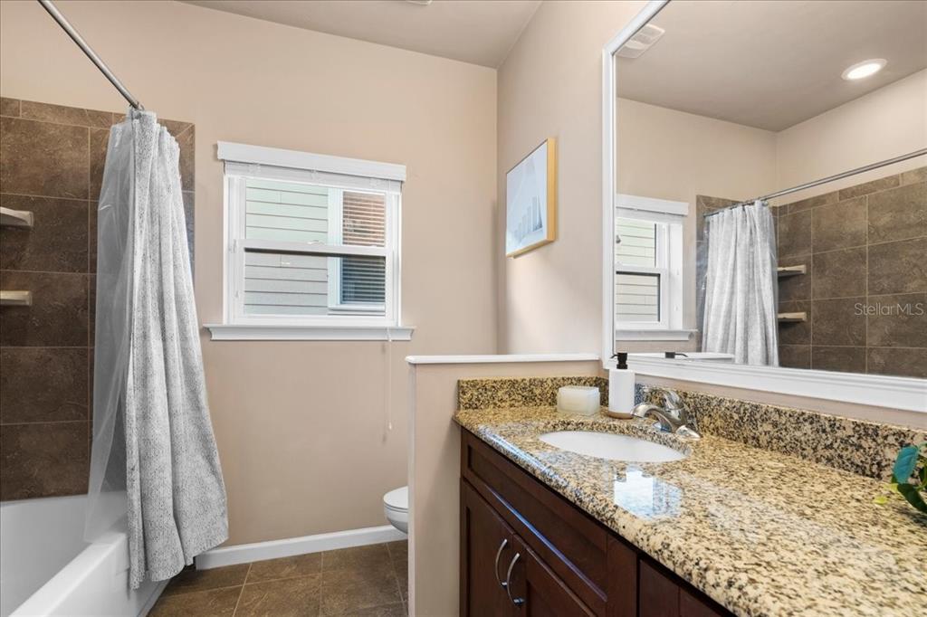 9834 Northwest 17th Road Gainesville, FL 32606 - Photo 25 of 51 a bathroom with a granite countertop sink a mirror and a shower