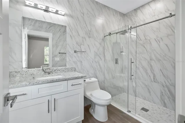 a bathroom with a granite countertop sink toilet a mirror and shower