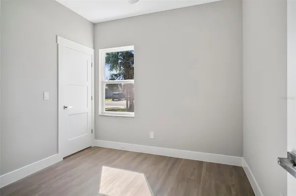 a view of an empty room with wooden floor and a window