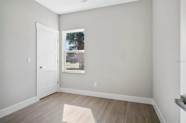 a view of an empty room with wooden floor and a window