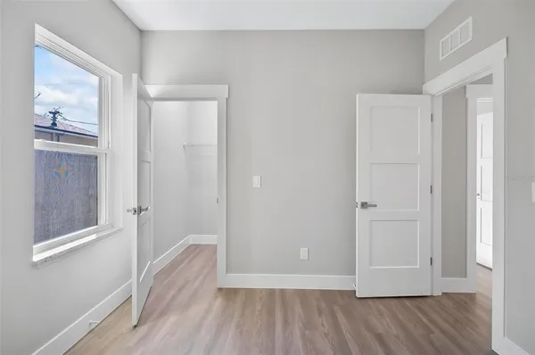 a view of a hallway with wooden floor and closet