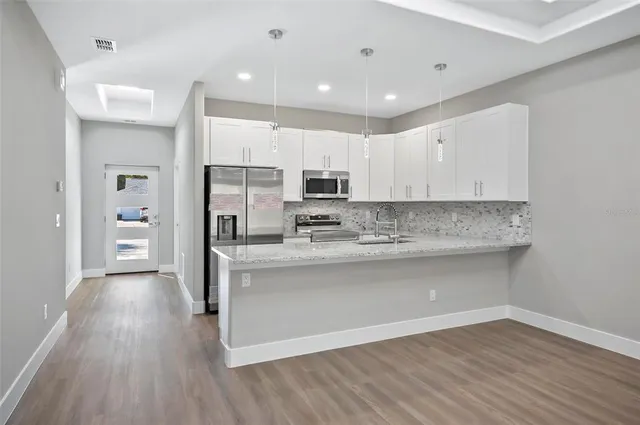a view of kitchen with granite countertop cabinets and refrigerator