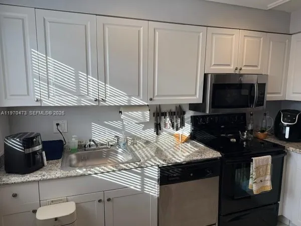a kitchen with granite countertop a sink a stove and cabinets
