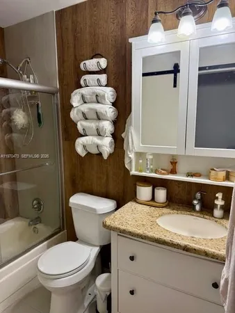 a bathroom with a granite countertop toilet sink and mirror