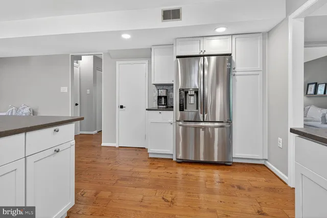 a kitchen with stainless steel appliances granite countertop a sink a stove a refrigerator and island with wooden floor