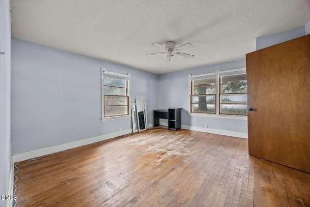 a view of an empty room with a window and wooden floor