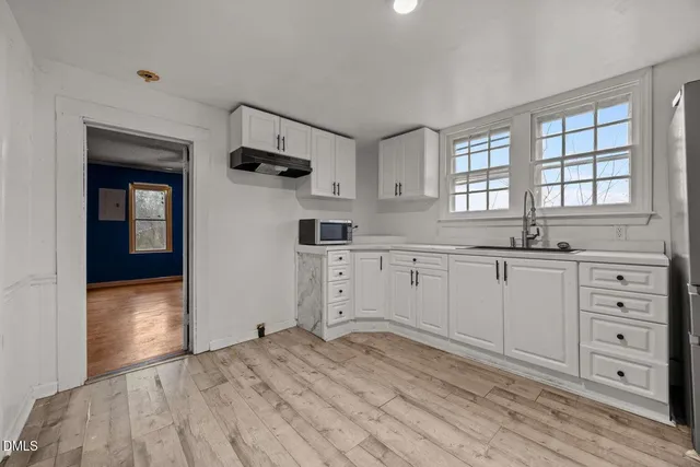 a kitchen with granite countertop a sink cabinets and a wooden floor