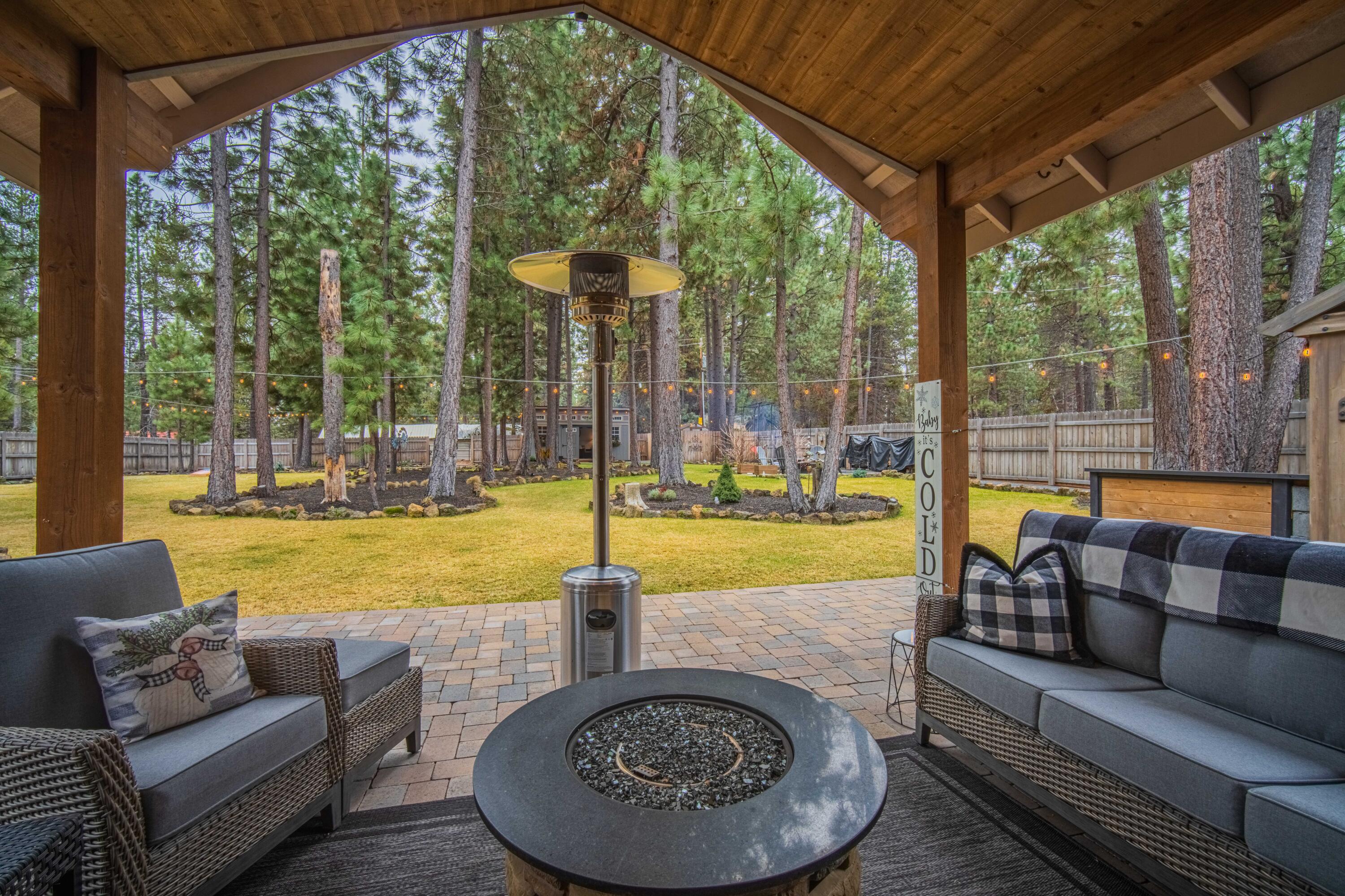 16927 Covina Road Bend, OR 97707 - Photo 27 of 54 Covered patio in this Bend, Oregon backyard oasis with fire table seating, timber detail, and a peaceful view across the beautifully landscaped yard.