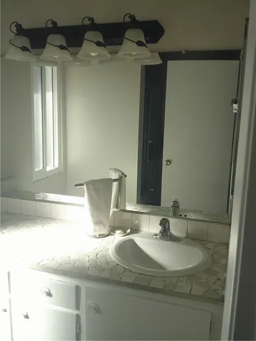 a bathroom with a granite countertop sink and a mirror