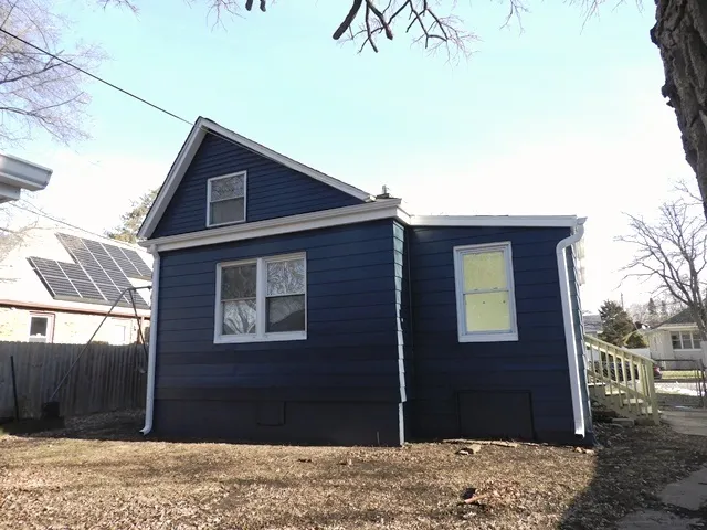 a backyard of a house with large trees and wooden fence