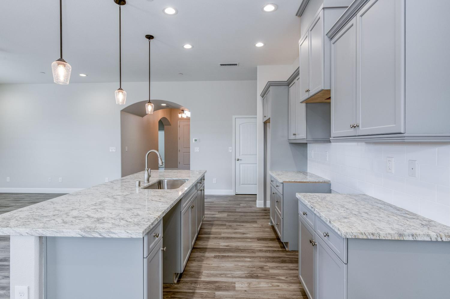 a kitchen with granite countertop kitchen island a sink stainless steel appliances and white cabinets