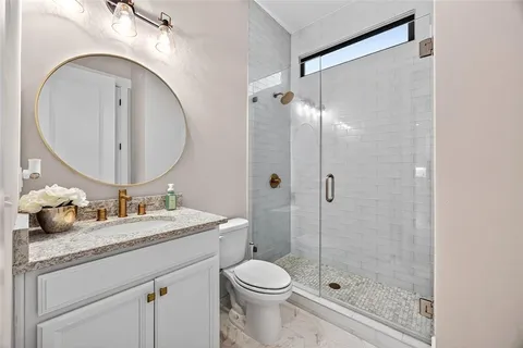 a bathroom with a granite countertop sink toilet mirror and shower