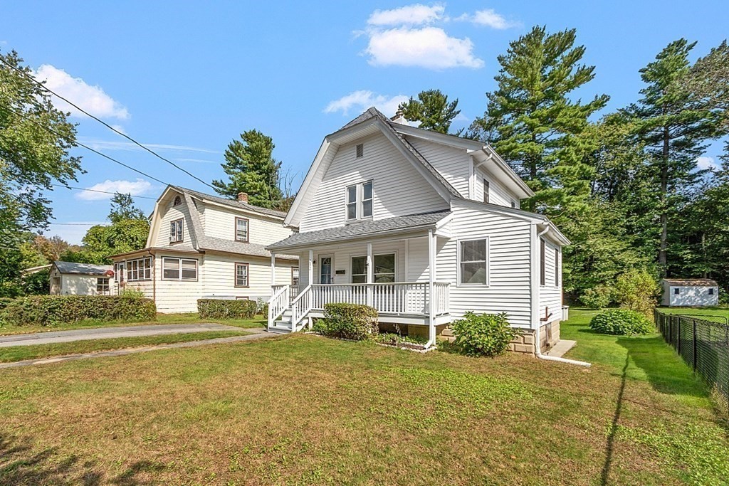 a view of a white house next to a yard with plants and trees