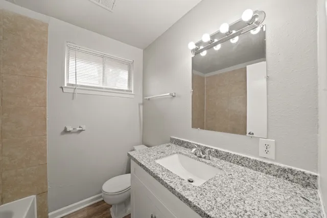 a bathroom with a granite countertop sink a toilet and a mirror