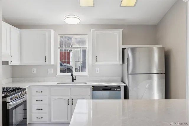 a kitchen with a refrigerator a sink and white cabinets
