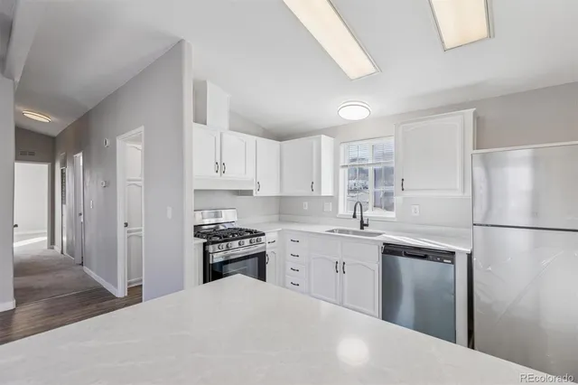 a kitchen with a sink a refrigerator and white cabinets