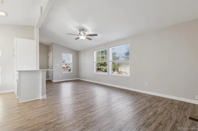 an empty room with wooden floor and windows