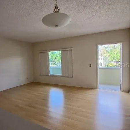 an empty room with wooden floor cabinet and windows
