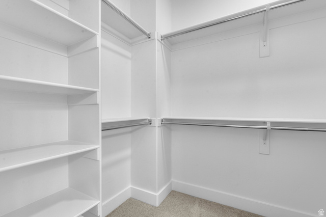 5644 Ibis Road Tooele, UT 84074 - Photo 19 of 19 Walk-in closet featuring white built-in shelving, multiple hanging rods, and light-toned carpet flooring
