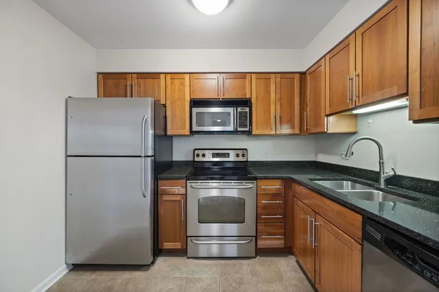 a kitchen with granite countertop wood cabinets stainless steel appliances and a sink