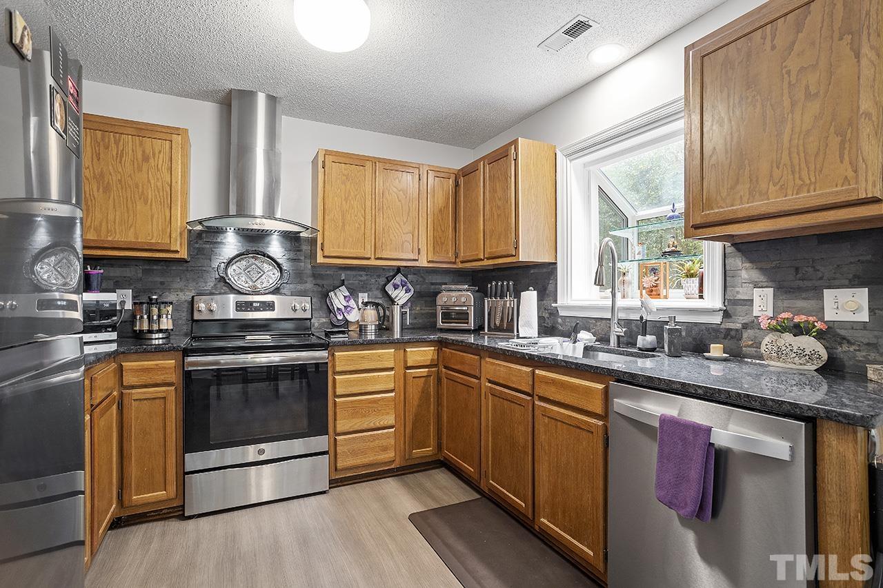 4604 Fox Road Raleigh, NC 27616 - Photo 5 of 29 a kitchen with stainless steel appliances granite countertop wooden cabinets sink and stove top oven