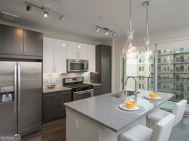 a kitchen with stainless steel appliances granite countertop a stove top oven a sink dishwasher a dining table and chairs with wooden floors