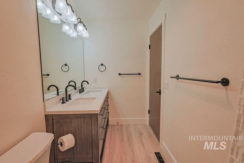640 Morrison Street Twin Falls, ID 83301 - Photo 23 of 30 Bathroom featuring a dual vanity with a light-toned countertop, matte black fixtures, and wood-finish flooring