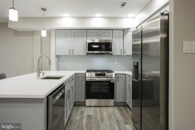 a kitchen with stainless steel appliances a stove a sink and a refrigerator